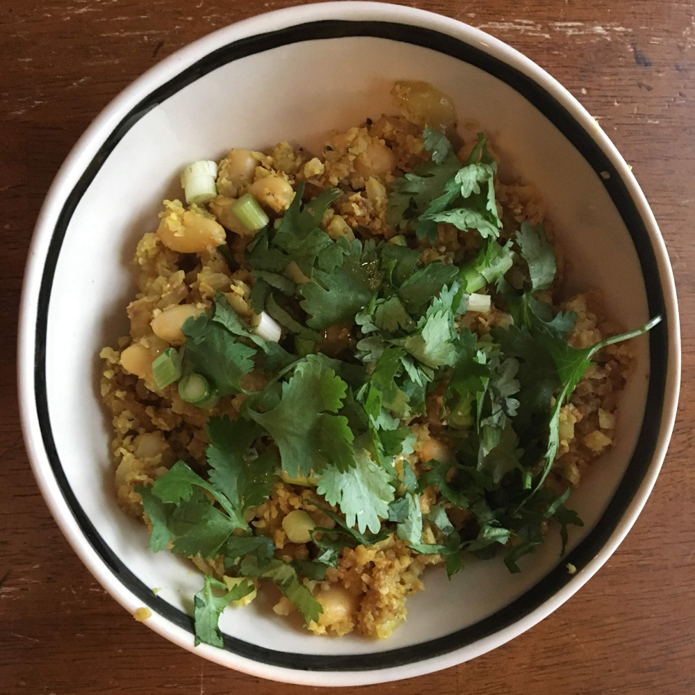 Curried vegan cauliflower rice with cilantro and spring onions. 