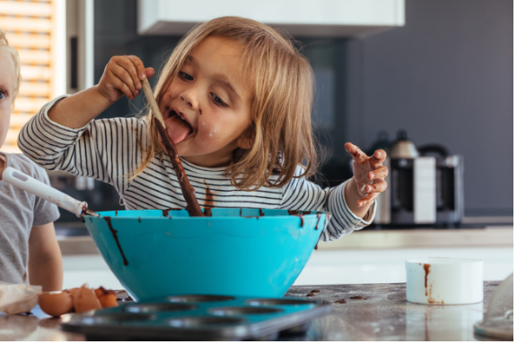 picture of little girl eating from a cake mixing bowl