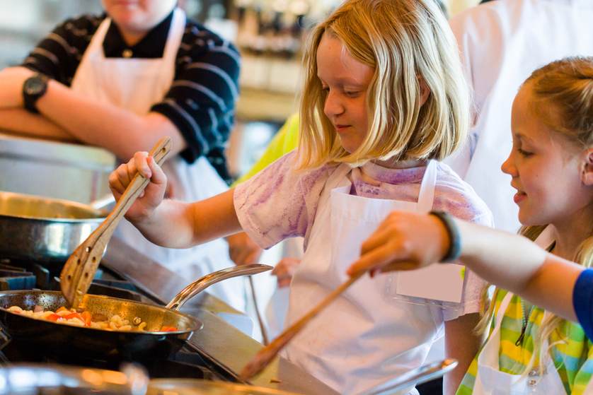 young kids cooking food in a pan