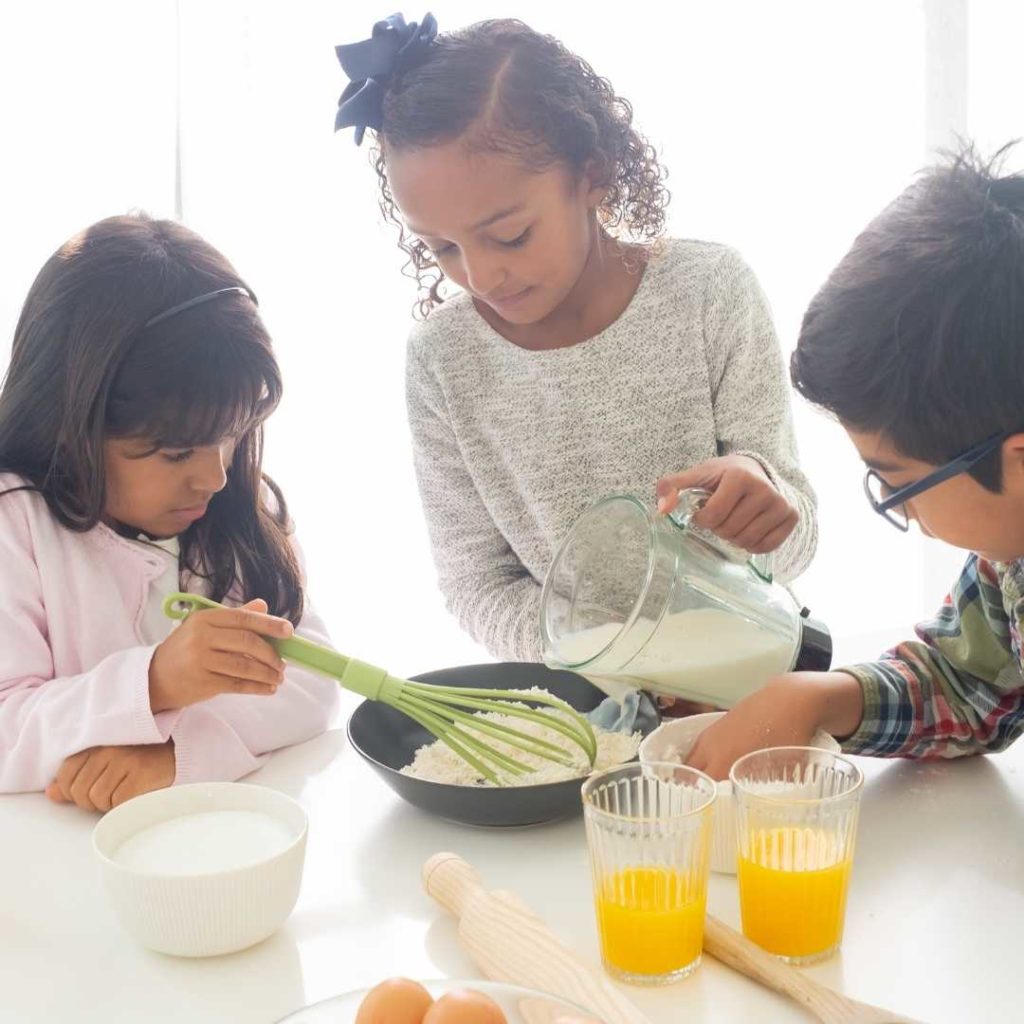 3 children preparing breakfast with eggs and orange juice