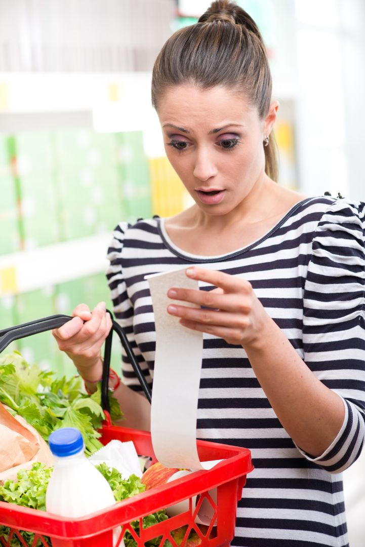 Young woman in striped shirt and pony tail is shocked at her grocery bill