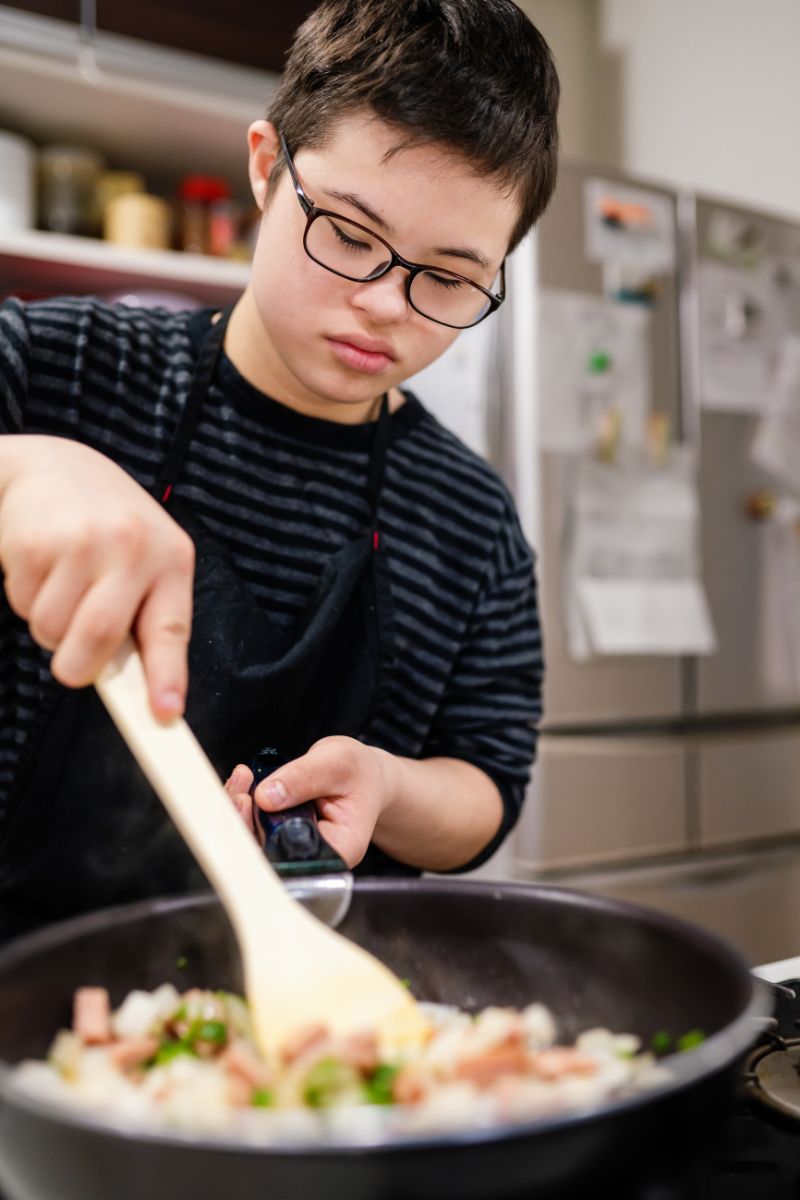 young asian man cooking with a large cast iron pan